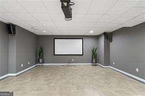 cinema room with baseboards and a drop ceiling