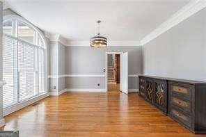 unfurnished dining area with a healthy amount of sunlight, an inviting chandelier, baseboards, and wood finished floors