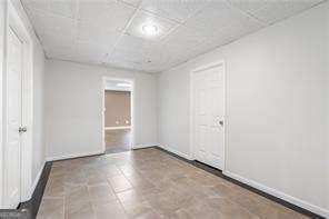 unfurnished room with a paneled ceiling and baseboards