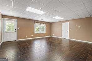 interior space featuring a paneled ceiling and baseboards