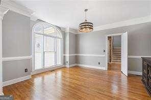unfurnished dining area featuring baseboards, stairway, an inviting chandelier, and wood finished floors