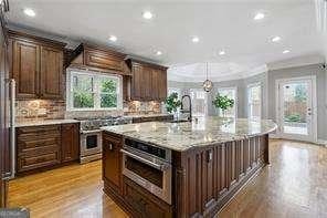 kitchen featuring a sink, ornamental molding, a kitchen island with sink, recessed lighting, and stainless steel appliances