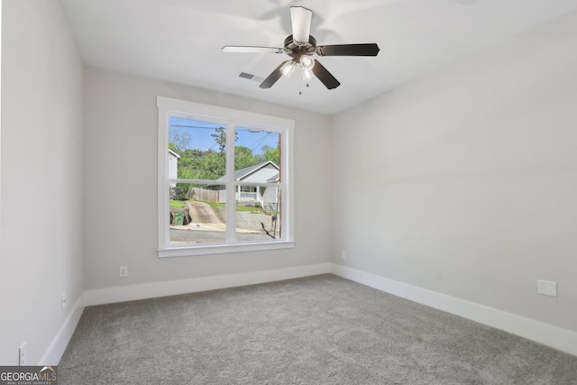 carpeted empty room with visible vents, baseboards, and a ceiling fan
