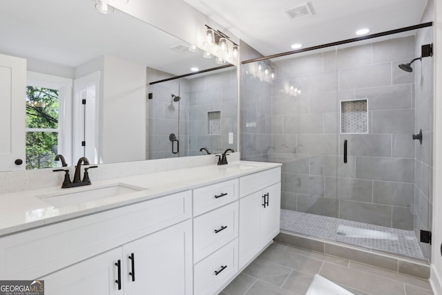 full bathroom featuring a shower stall, double vanity, visible vents, and a sink