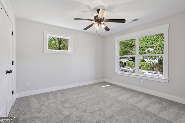 carpeted empty room featuring visible vents, baseboards, and ceiling fan