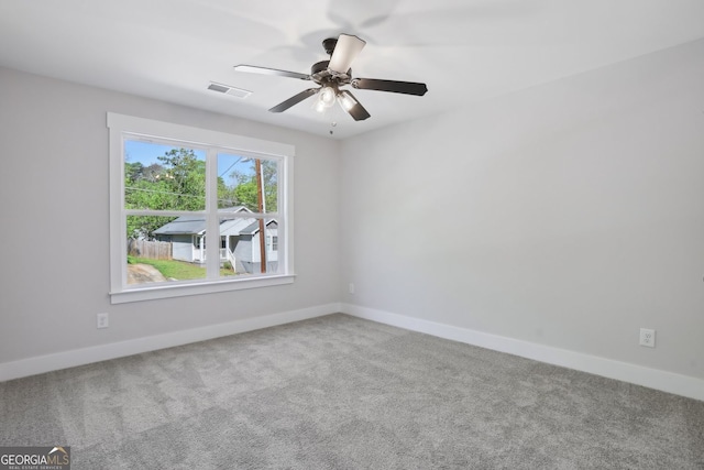 carpeted empty room with visible vents, baseboards, and ceiling fan