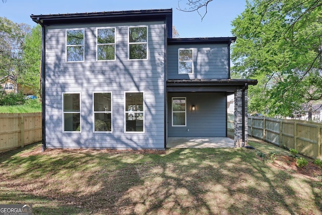 rear view of house with a patio, a fenced backyard, and a lawn