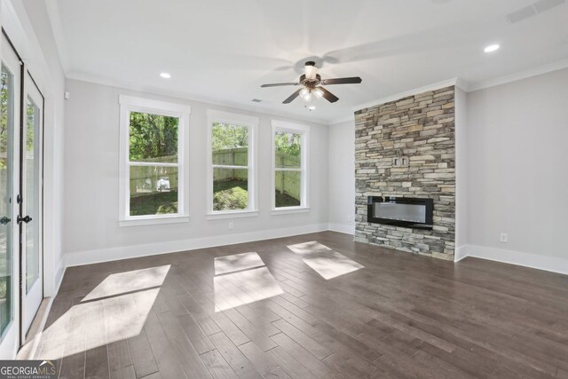 unfurnished living room with visible vents, ornamental molding, a stone fireplace, a ceiling fan, and dark wood-style floors