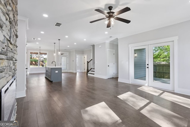 unfurnished living room featuring a fireplace, visible vents, a sink, and dark wood-style floors