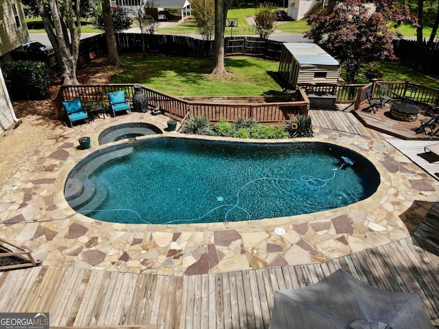 view of pool with a fenced backyard, a wooden deck, a pool with connected hot tub, and a lawn