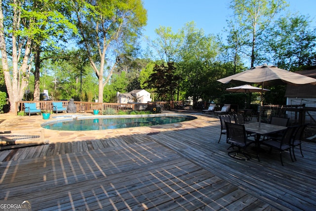 view of swimming pool with a wooden deck, outdoor dining space, and a fenced in pool