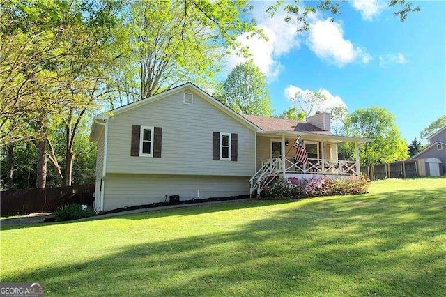 rear view of property featuring a lawn, a porch, a chimney, and fence