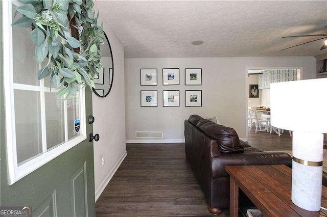 interior space with visible vents, dark wood-type flooring, baseboards, a textured ceiling, and ceiling fan