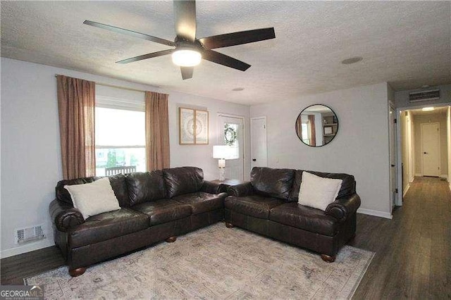 living area with a textured ceiling, baseboards, visible vents, wood finished floors, and ceiling fan