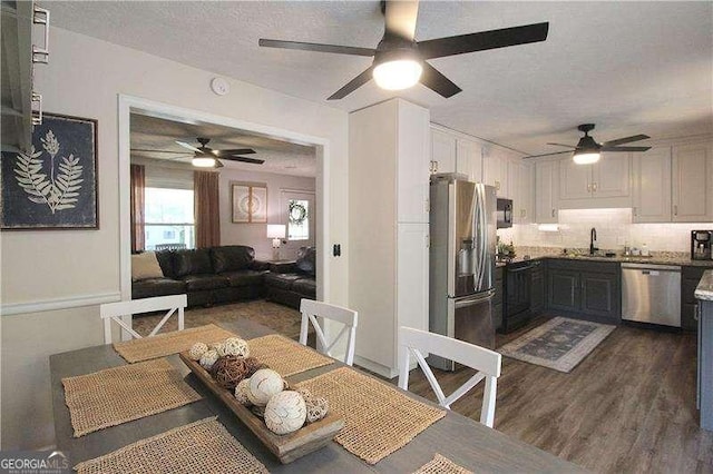 dining space with ceiling fan, dark wood-type flooring, and a textured ceiling