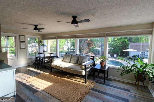 sunroom with baseboards, wood finished floors, and a textured ceiling