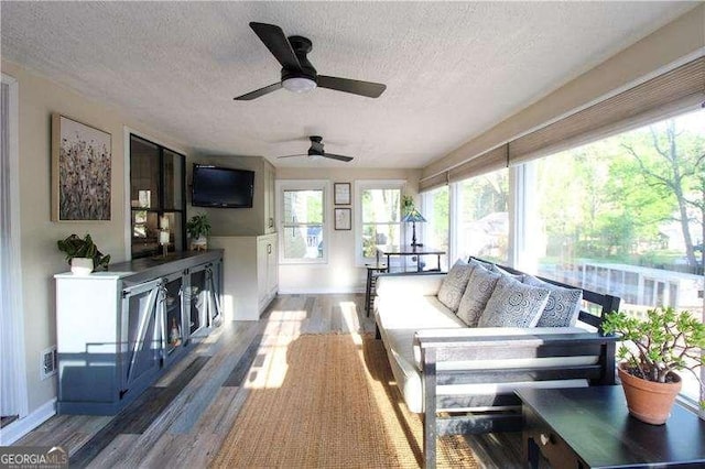 sunroom featuring a textured ceiling, wood finished floors, and baseboards