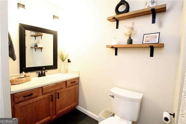 bathroom with toilet, vanity, and baseboards