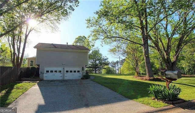 view of side of property with concrete driveway, fence, a yard, and a garage