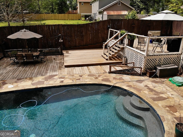 view of swimming pool featuring a fenced in pool, outdoor dining space, a deck, and a fenced backyard