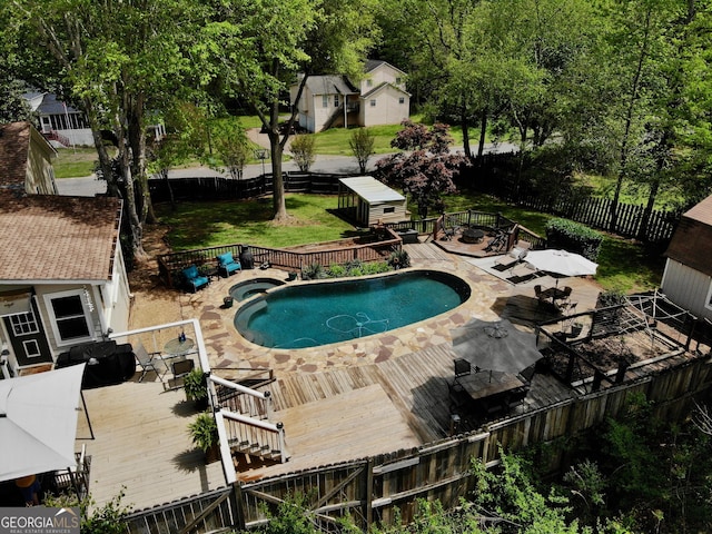 view of swimming pool with an outdoor structure, a shed, a wooden deck, and a fenced backyard
