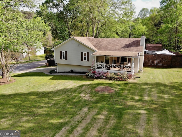 back of house with a lawn, fence, covered porch, and a chimney