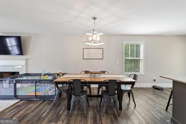 dining space featuring dark wood-type flooring, a chandelier, a high end fireplace, and baseboards