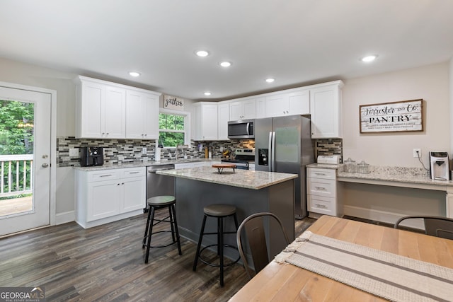 kitchen with stainless steel appliances, white cabinets, a kitchen bar, and decorative backsplash