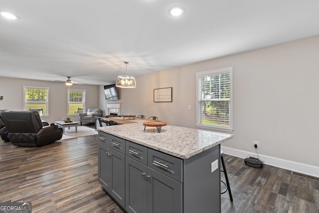 kitchen with dark wood-style floors, a wealth of natural light, a kitchen breakfast bar, and gray cabinetry