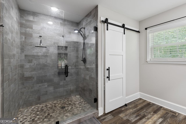 full bathroom featuring a shower stall, wood finished floors, baseboards, and visible vents