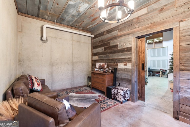 living area with concrete floors, wooden walls, and a notable chandelier