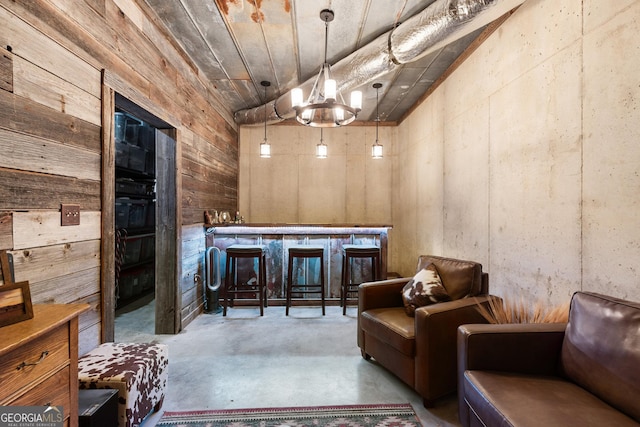 interior space with a bar, wood walls, and concrete flooring