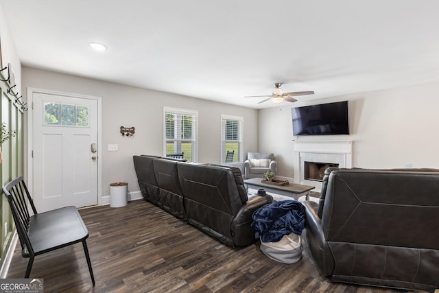 living area with ceiling fan, a fireplace, dark wood finished floors, and baseboards