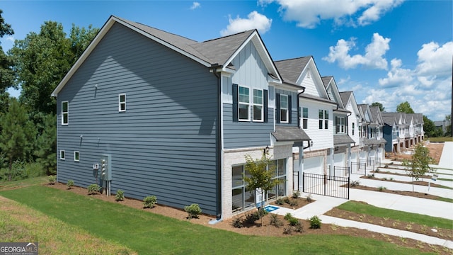 38 Buckingham Ln Unit 232, Hoschton, GA 30548 - view of side of property featuring board and batten siding, a lawn, an attached garage, driveway, and a residential view