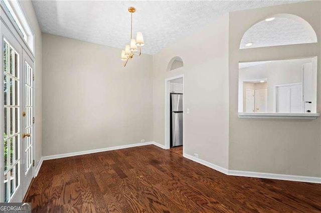 spare room featuring baseboards, a chandelier, wood finished floors, and a textured ceiling