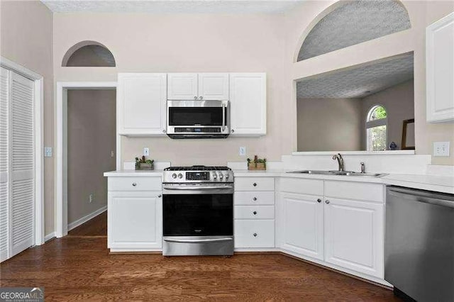 kitchen featuring stainless steel appliances, light countertops, a sink, and white cabinetry