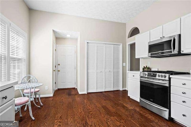 kitchen featuring baseboards, light countertops, appliances with stainless steel finishes, dark wood-style floors, and white cabinetry