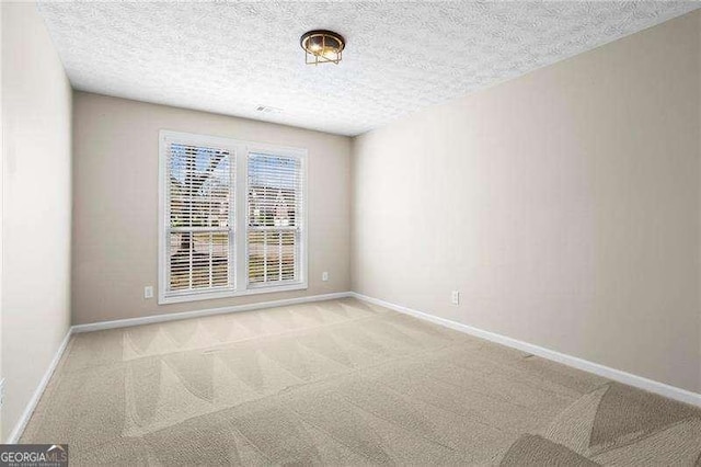 spare room with a textured ceiling, baseboards, and carpet