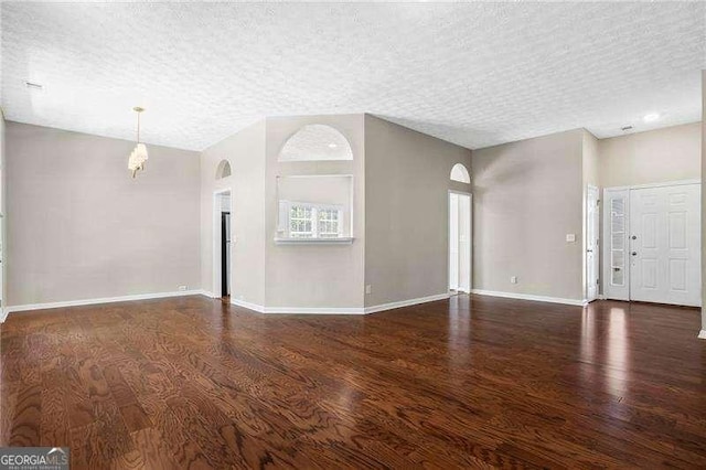 unfurnished living room with baseboards, an inviting chandelier, wood finished floors, and a textured ceiling