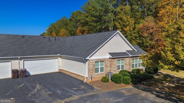4573 Caleb Xing Unit 20, Powder Springs, GA 30127 - view of front facade with central AC, an attached garage, aphalt driveway, brick siding, and roof with shingles