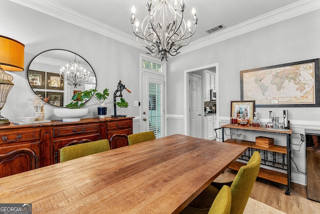 dining area featuring visible vents, an inviting chandelier, ornamental molding, wainscoting, and wood finished floors