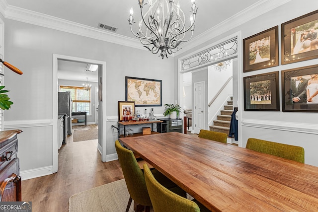 dining space with crown molding, visible vents, wood finished floors, stairs, and a notable chandelier