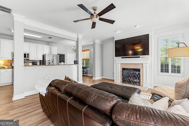 living room with crown molding, a ceiling fan, visible vents, and a wealth of natural light