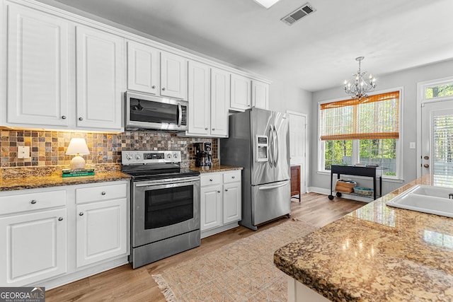 kitchen with light wood-type flooring, an inviting chandelier, white cabinetry, and appliances with stainless steel finishes
