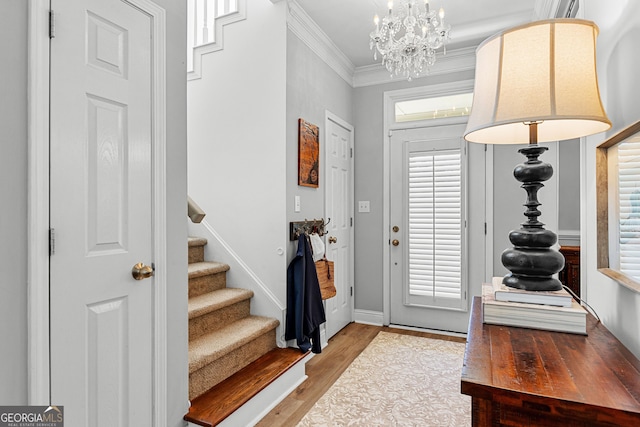 entryway featuring crown molding, stairway, a notable chandelier, and wood finished floors