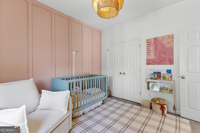 bedroom featuring a nursery area, a closet, and light colored carpet