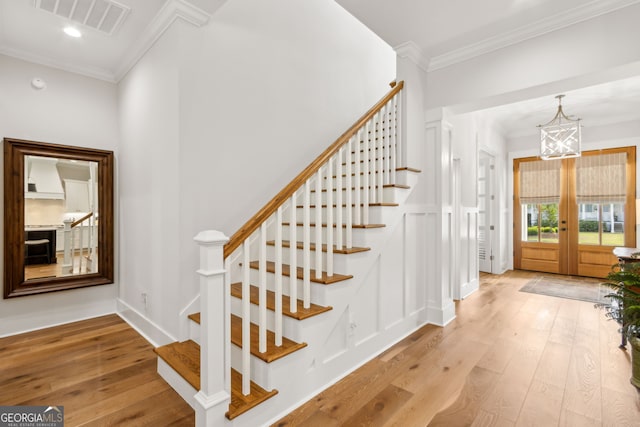 105 Whispering Oaks Ln, Saint Marys, GA 31558 - staircase featuring crown molding, visible vents, french doors, wood-type flooring, and a notable chandelier