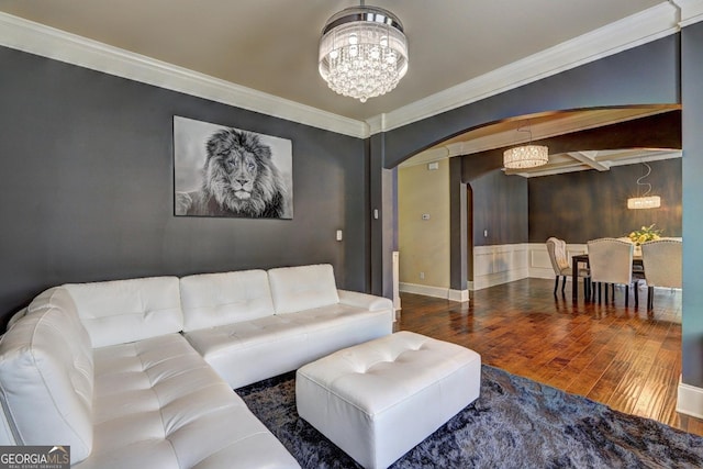 living area with an inviting chandelier, arched walkways, ornamental molding, wood finished floors, and baseboards