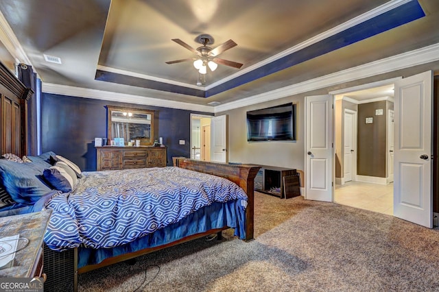carpeted bedroom featuring a raised ceiling, crown molding, ceiling fan, and visible vents