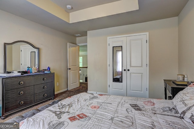 bedroom featuring a tray ceiling, baseboards, a closet, and carpet